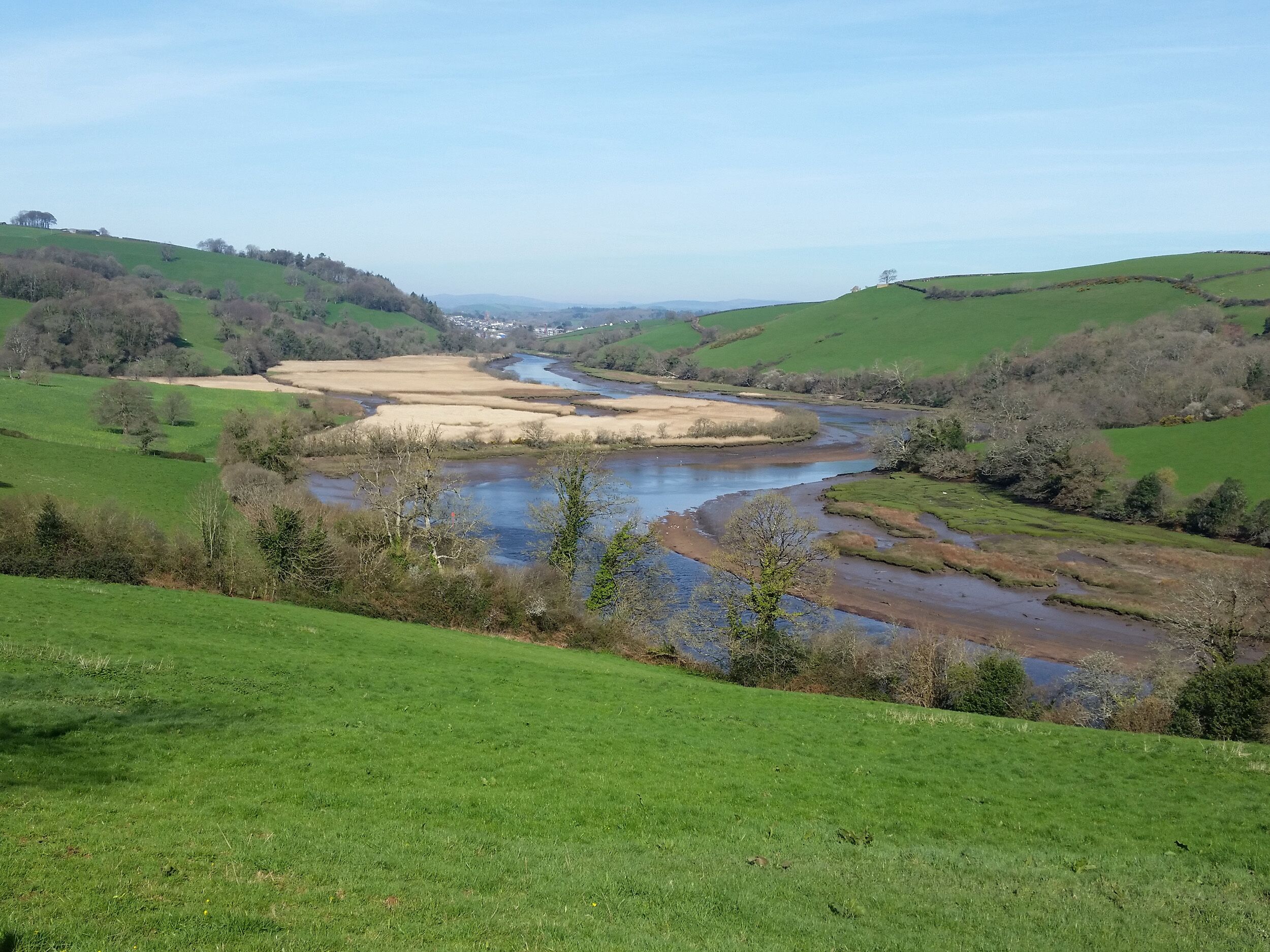 A river flowing through a green valley with hills on either side.