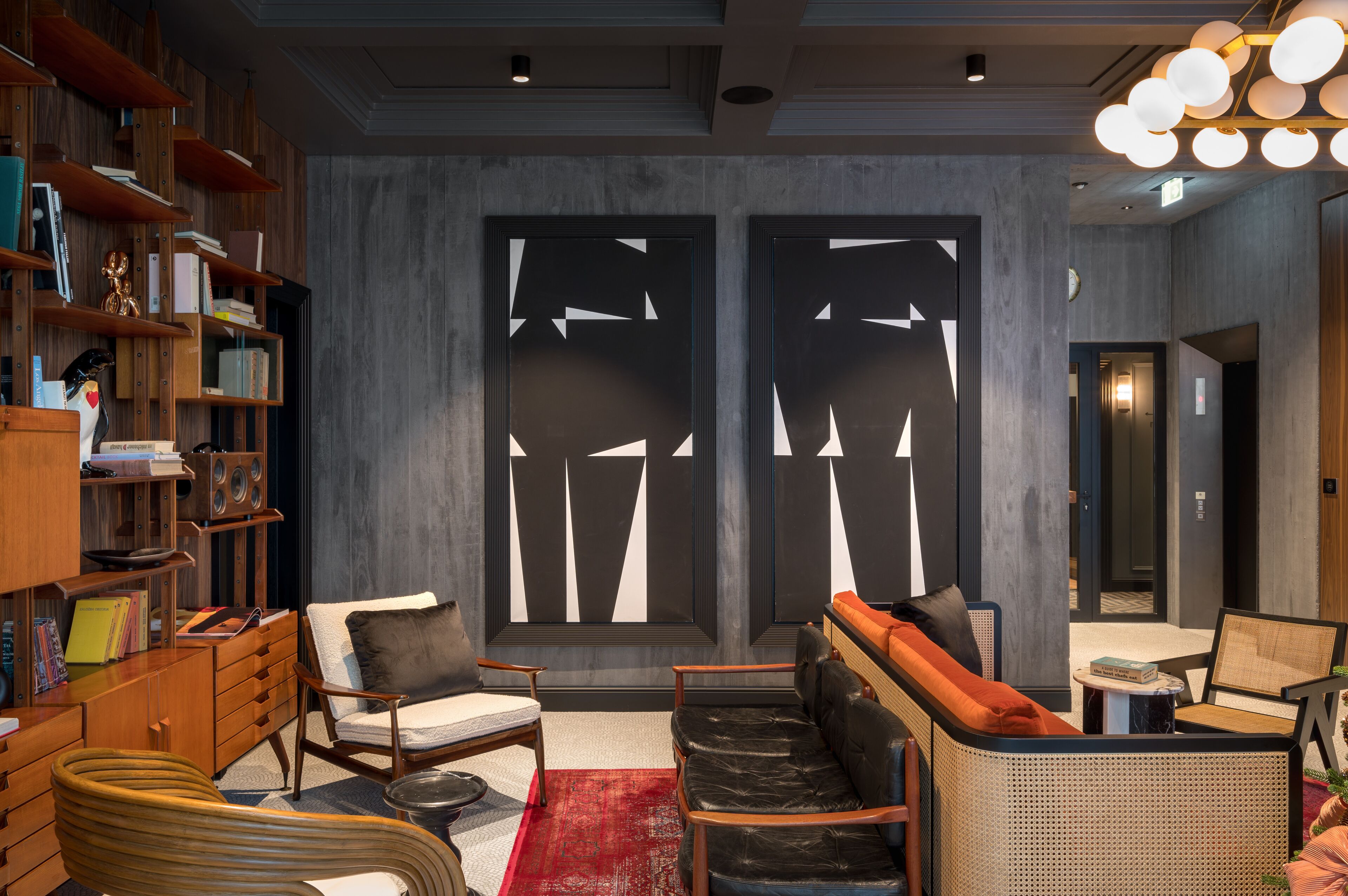 A modern interior with a bookshelf, seating area, and abstract wall art.
