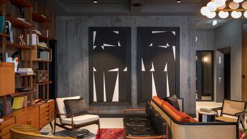 A modern interior with a bookshelf, seating area, and abstract wall art.