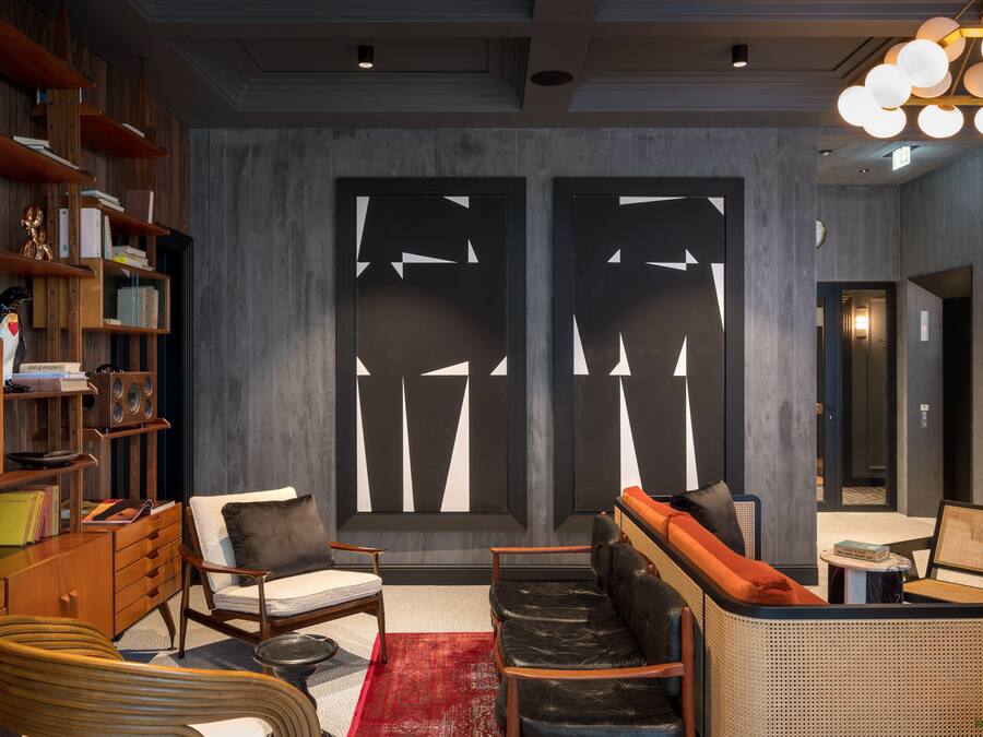 A modern interior with a bookshelf, seating area, and abstract wall art.