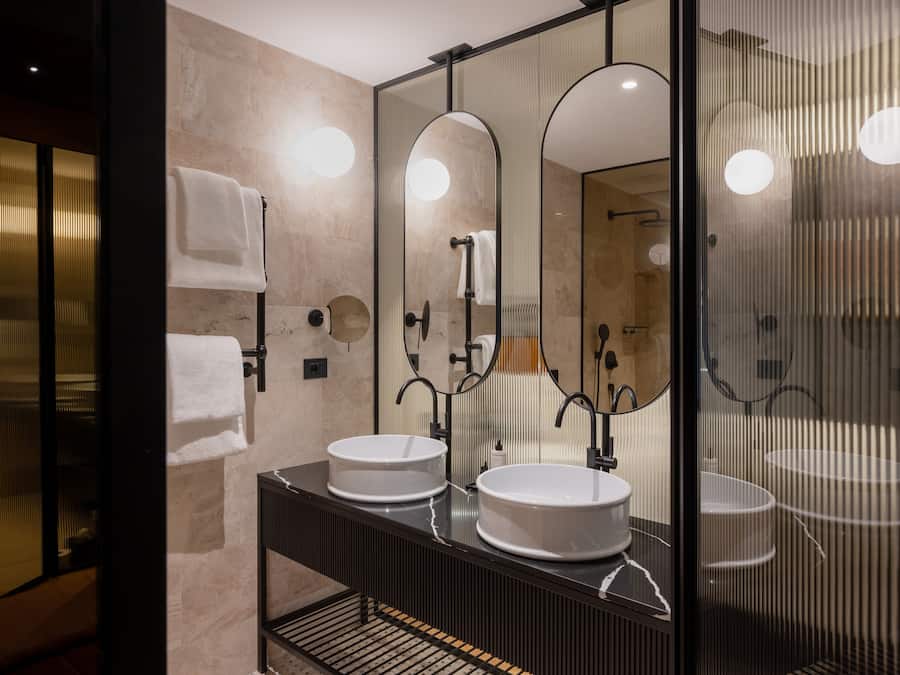 A modern bathroom with two sinks, a large mirror, and a glass shower enclosure.