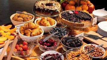 Une table de buffet proposant une variété d’aliments, notamment des fruits, des pâtisseries et des desserts.