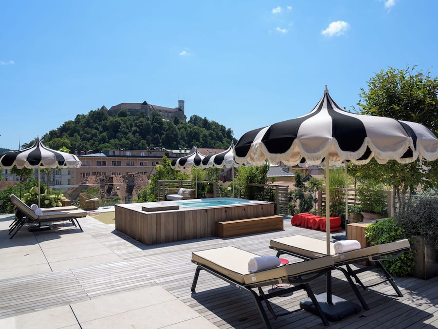 Eine Dachterrasse mit Liegestühlen, einem Whirlpool und Sonnenschirmen.