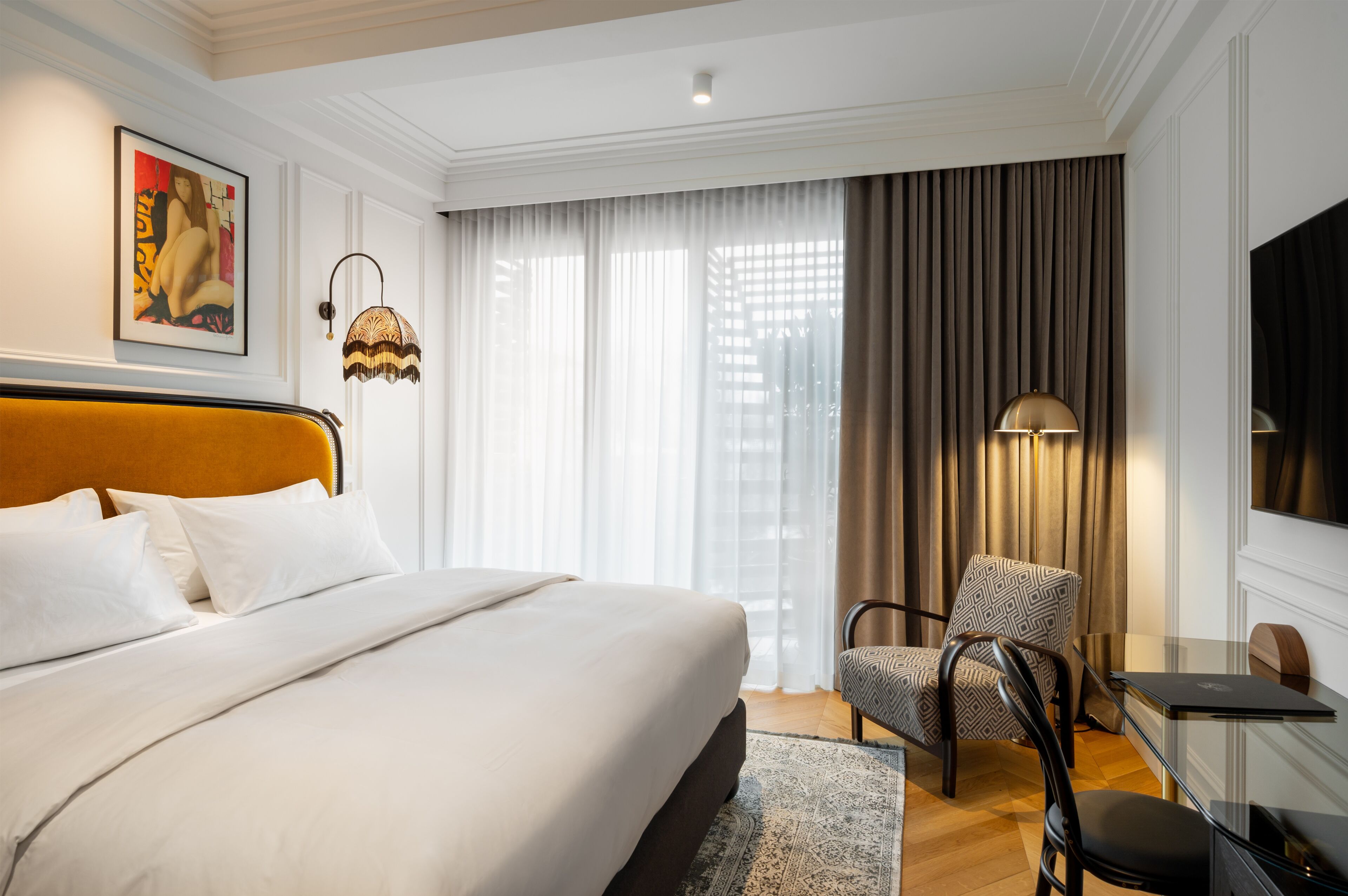 Une chambre d’hôtel avec un grand lit, un bureau avec un ordinateur portable, une chaise et une télévision.