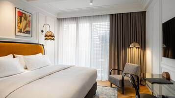 Une chambre d’hôtel avec un grand lit, un bureau avec un ordinateur portable, une chaise et une télévision.
