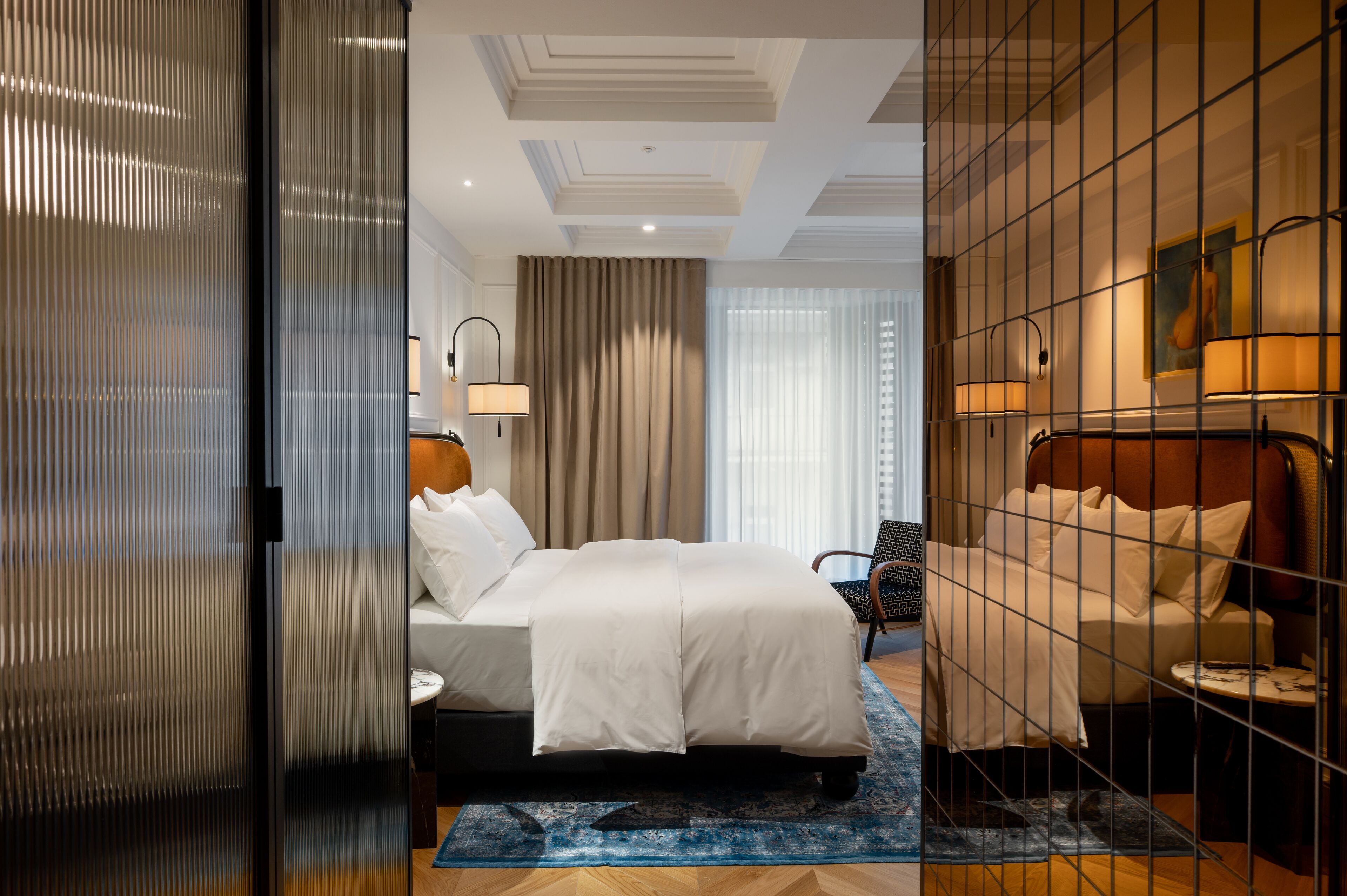 A modern hotel room with a large bed, a desk, and a chair.