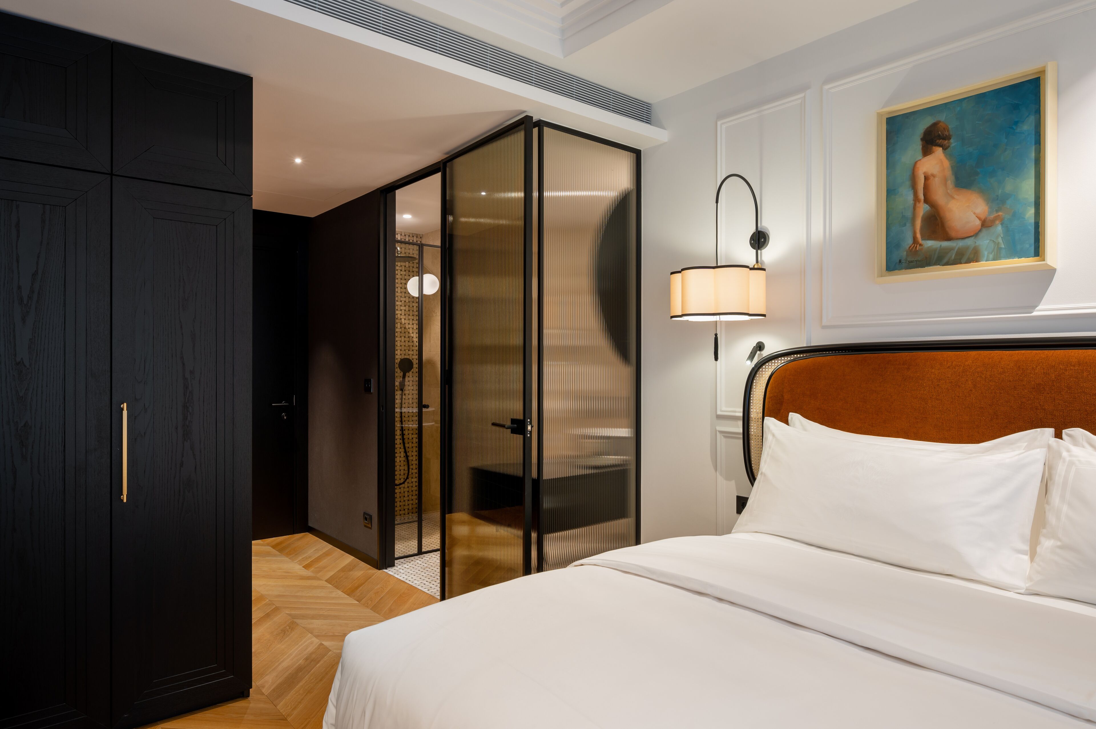 Camera d'albergo con un letto, un armadio, una porta scorrevole in vetro, un quadro appeso e una lampada da comodino.