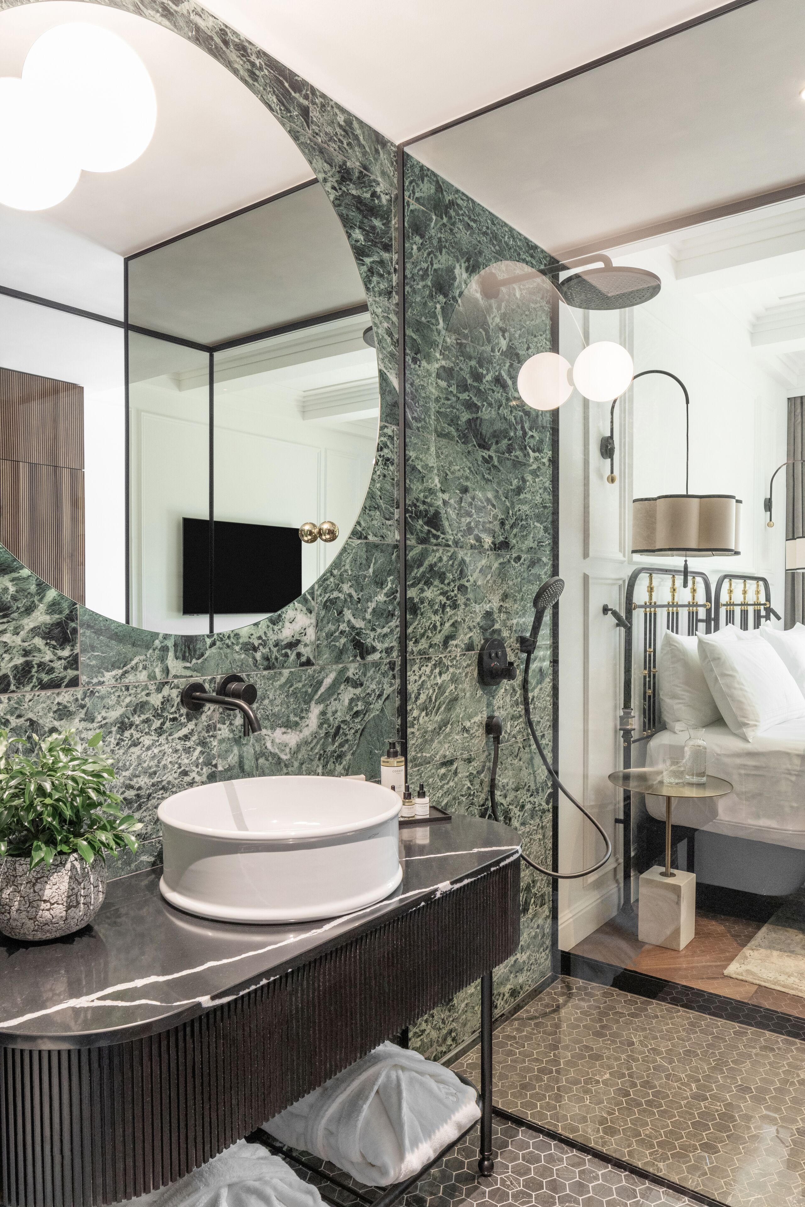 A modern bathroom with a large mirror, a round sink, and a shower area.