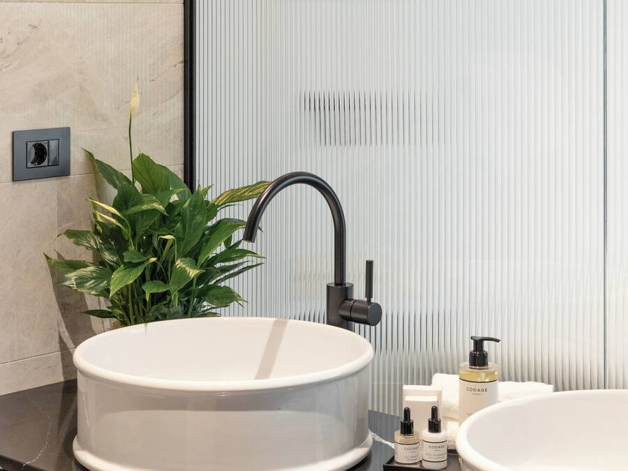 A modern bathroom with two sinks, a black faucet, and a potted plant.