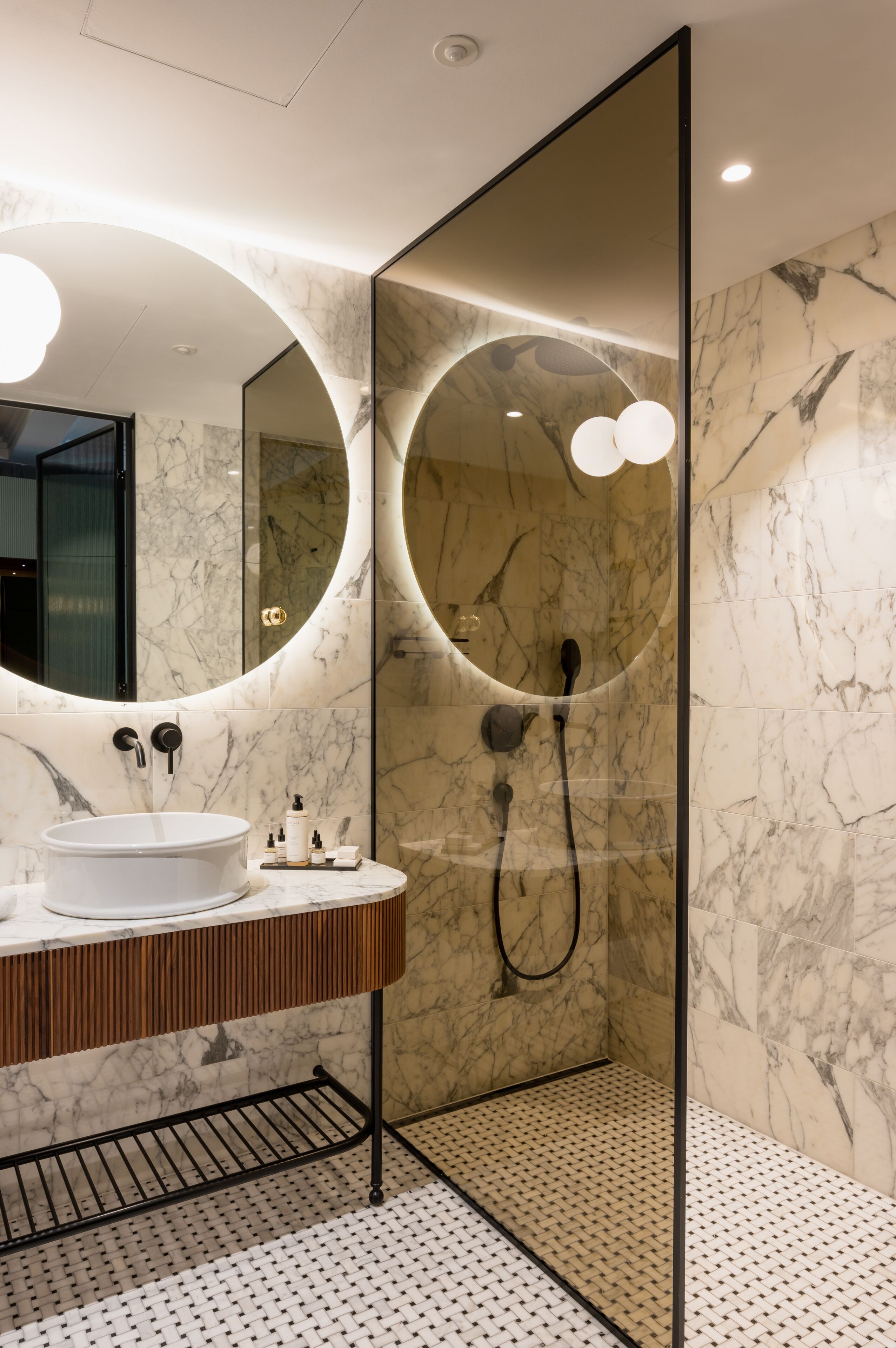 Un baño moderno con tocador de mármol, un espejo grande y zona de ducha.
