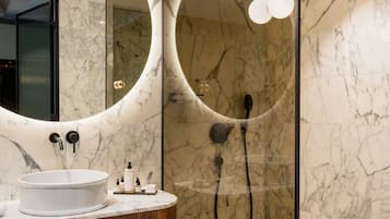 Un baño moderno con tocador de mármol, un espejo grande y zona de ducha.