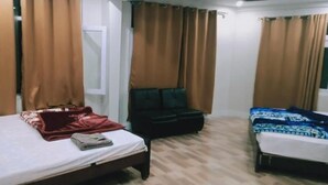 A hotel room with two beds, a sofa, and a window with curtains. - skardu eat and stay (Skardu baltistan)