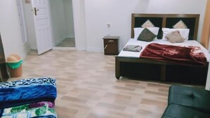 A bedroom with a bed, bedside table, and a chair. - skardu eat and stay (Skardu baltistan)