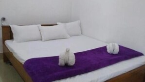 A single-bed room with a wooden frame, white bedding, and a purple blanket. - skardu eat and stay (Skardu baltistan)