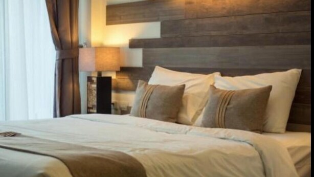 A hotel room with a large bed, a wooden headboard, and a bedside lamp. - skardu eat and stay (Skardu baltistan)