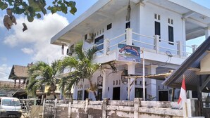 A two-story building with a balcony, a signboard, and a flag. - Hans Yoga Homestay (Kuta)