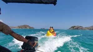 A person in a yellow inflatable raft being towed by a boat. - Hans Yoga Homestay (Kuta)