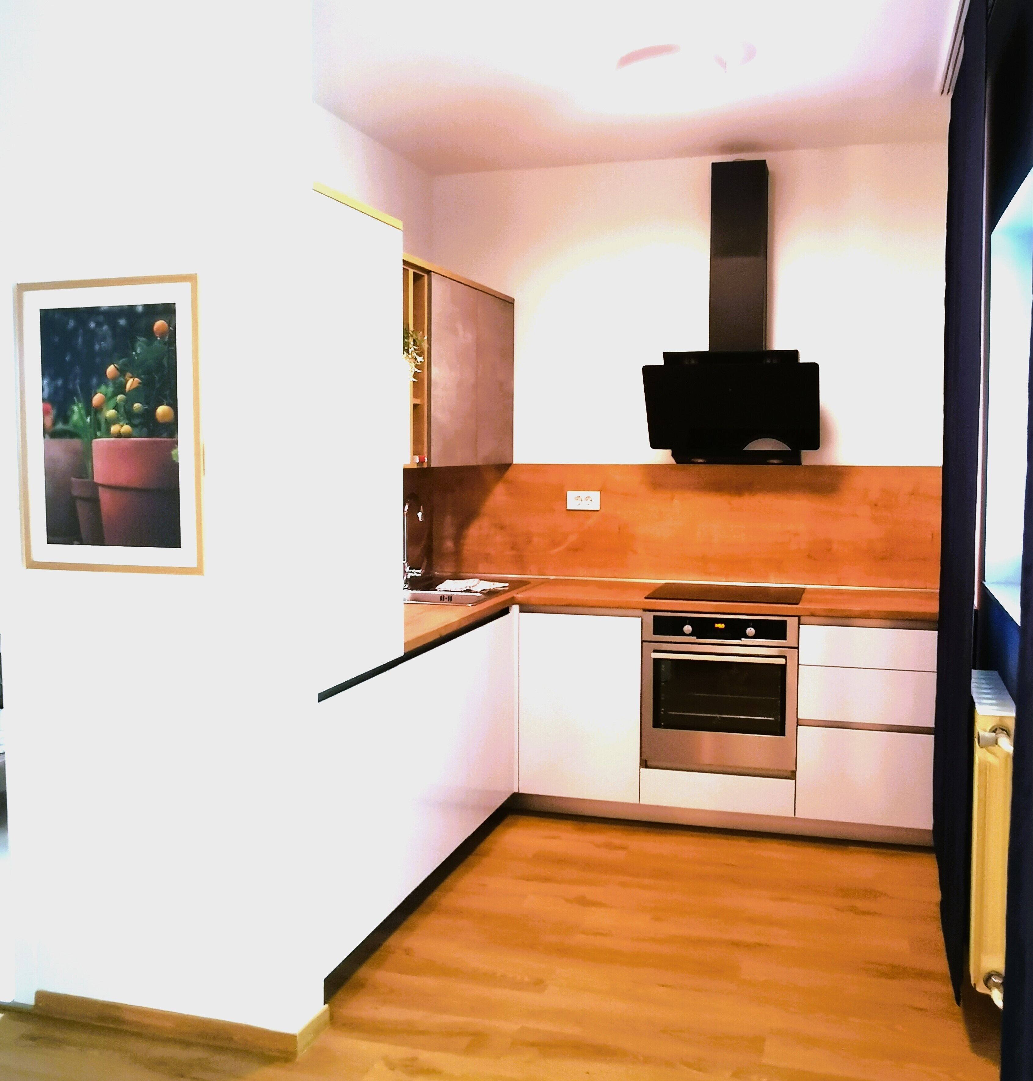 Una cocina compacta con horno integrado, microondas y una pequeña encimera.