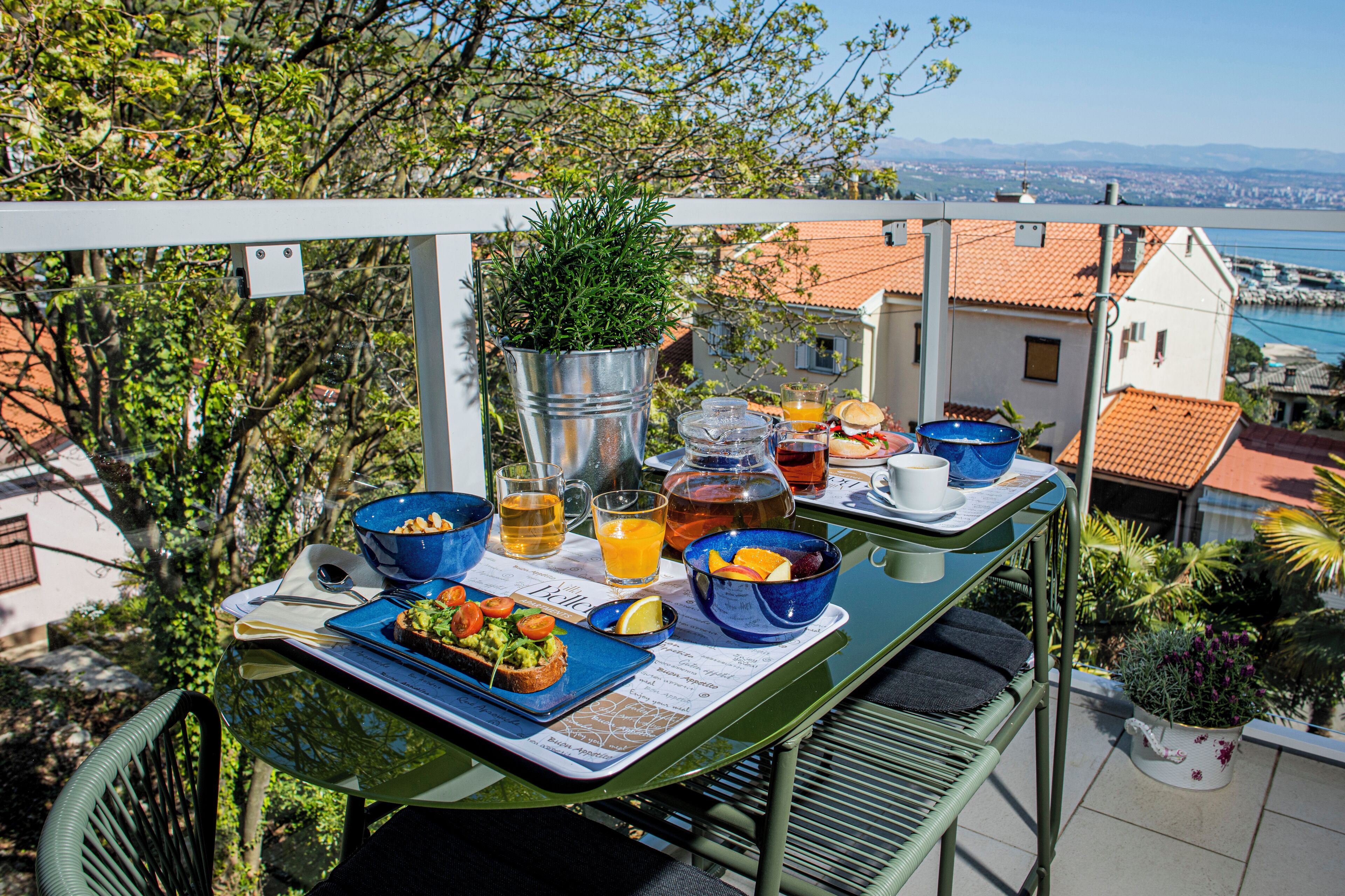 A balcony with a table set for breakfast, including bowls, glasses, and a menu.