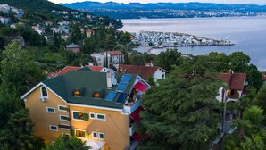 Un immeuble à plusieurs étages doté d’un toit végétalisé, de panneaux solaires et d’un balcon surmonté d’une auvent rouge.