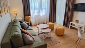 Un salon moderne comprenant un canapé, des poufs, une table basse et un téléviseur.
