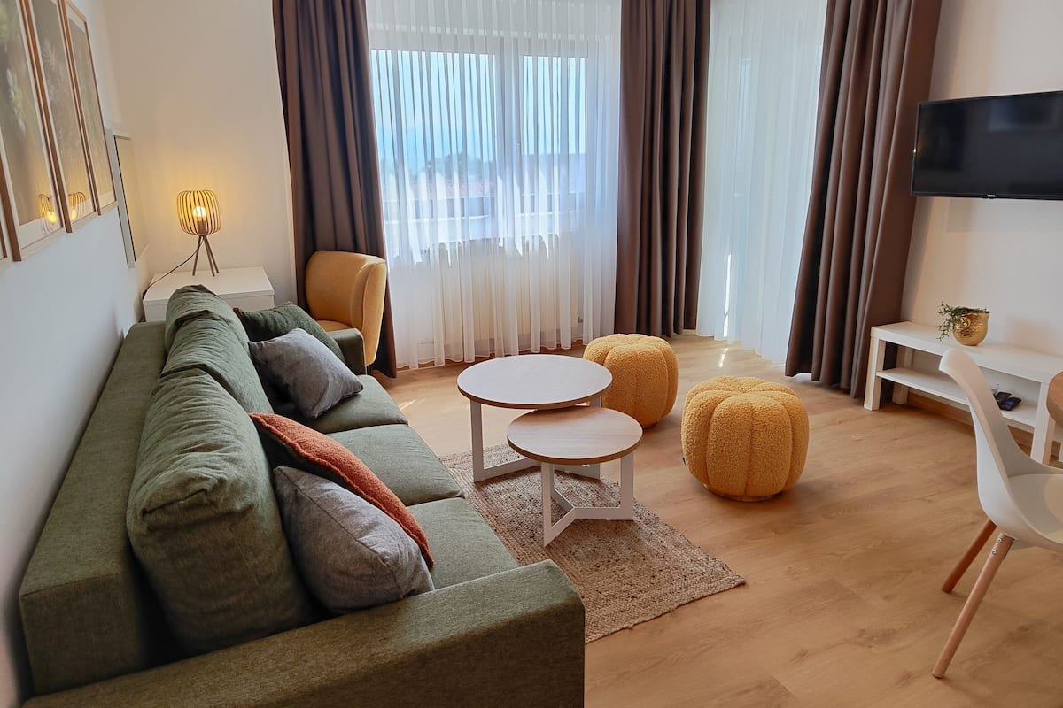 Un salon moderne comprenant un canapé, des poufs, une table basse et un téléviseur.