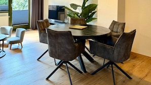 A modern dining area with a round table and six chairs, a potted plant, and a view of the outdoors through a window. - Frisch Renoviertes, Sehr Modernes Ferienhaus für die Ganze Familie! (Varel)