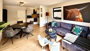 A modern living room with a dining area, a sofa set, and a large bull painting. - Frisch Renoviertes, Sehr Modernes Ferienhaus für die Ganze Familie! (Varel)