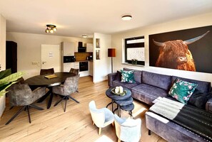 A modern living room with a dining area, a sofa set, and a large bull painting. - Frisch Renoviertes, Sehr Modernes Ferienhaus für die Ganze Familie! (Varel)