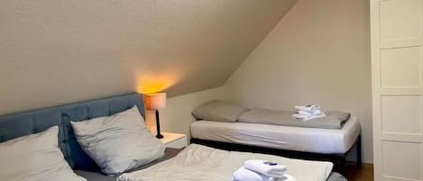 Ett hotellrum med två sängar, ett nattduksbord och en lampa.