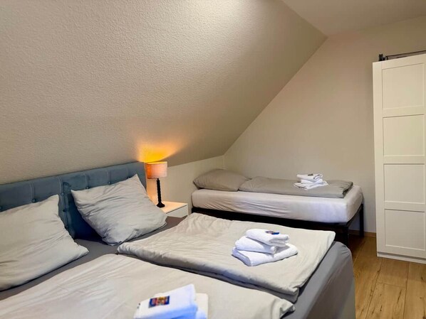 A hotel room with two beds, a nightstand, and a lamp. - Frisch Renoviertes, Sehr Modernes Ferienhaus für die Ganze Familie! (Varel)