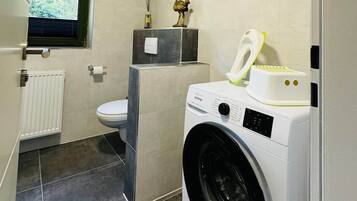 Un baño pequeño con lavadora, inodoro y un ventanal.