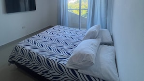 A bedroom with a bed, a flat-screen TV, and a window with curtains. - Apartment In Bello Horizonte (Santa Marta)