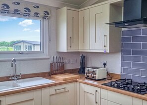 A kitchen with a sink, countertop, toaster, stove, and cabinets.