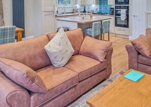 A modern living room with a sofa, a coffee table, and a kitchen area in the background.