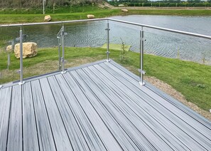 A wooden deck with metal railings overlooking a body of water.