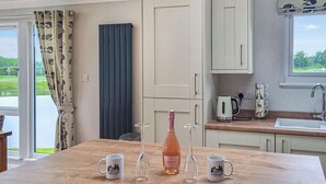 Une cuisine avec une table en bois, une bouteille de vin et deux tasses.