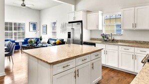 Una cocina moderna con armarios blancos, encimera de granito y electrodomésticos de acero inoxidable.