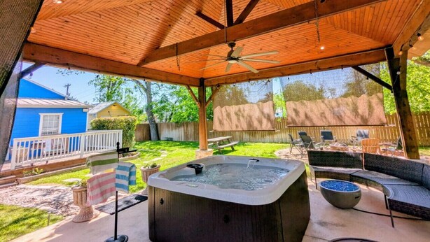 Un patio techado al aire libre con hidromasaje, zona de estar y techo de madera.