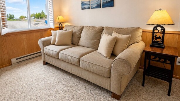 A beige sofa with cushions, a wooden side table with a lamp, and a window with blinds. - ML169 First Floor No Steps End Unit WiFi EZ Parking (Snowshoe)