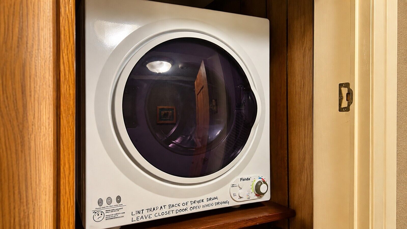 Vista frontal de una lavadora con panel de control, filtro de pelusas y puerta con manija.