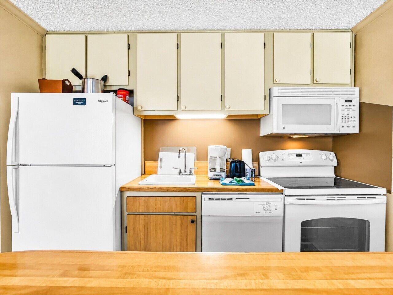A compact kitchenette with a refrigerator, microwave, stove, and dishwasher.