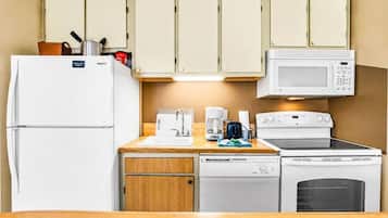 A compact kitchenette with a refrigerator, microwave, stove, and dishwasher.