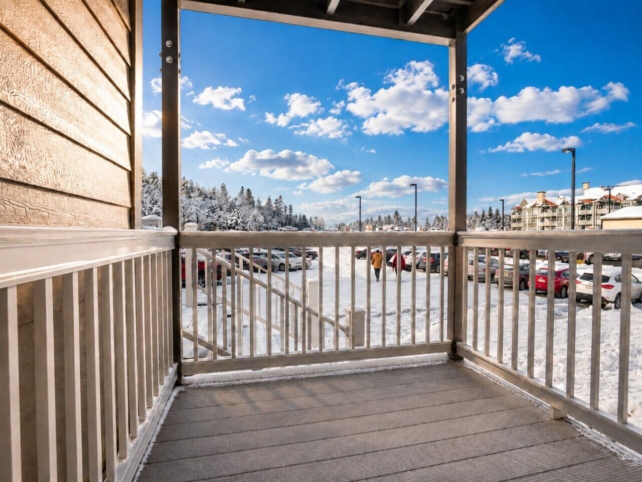 A covered outdoor area with a view of a parking lot and buildings in the background.