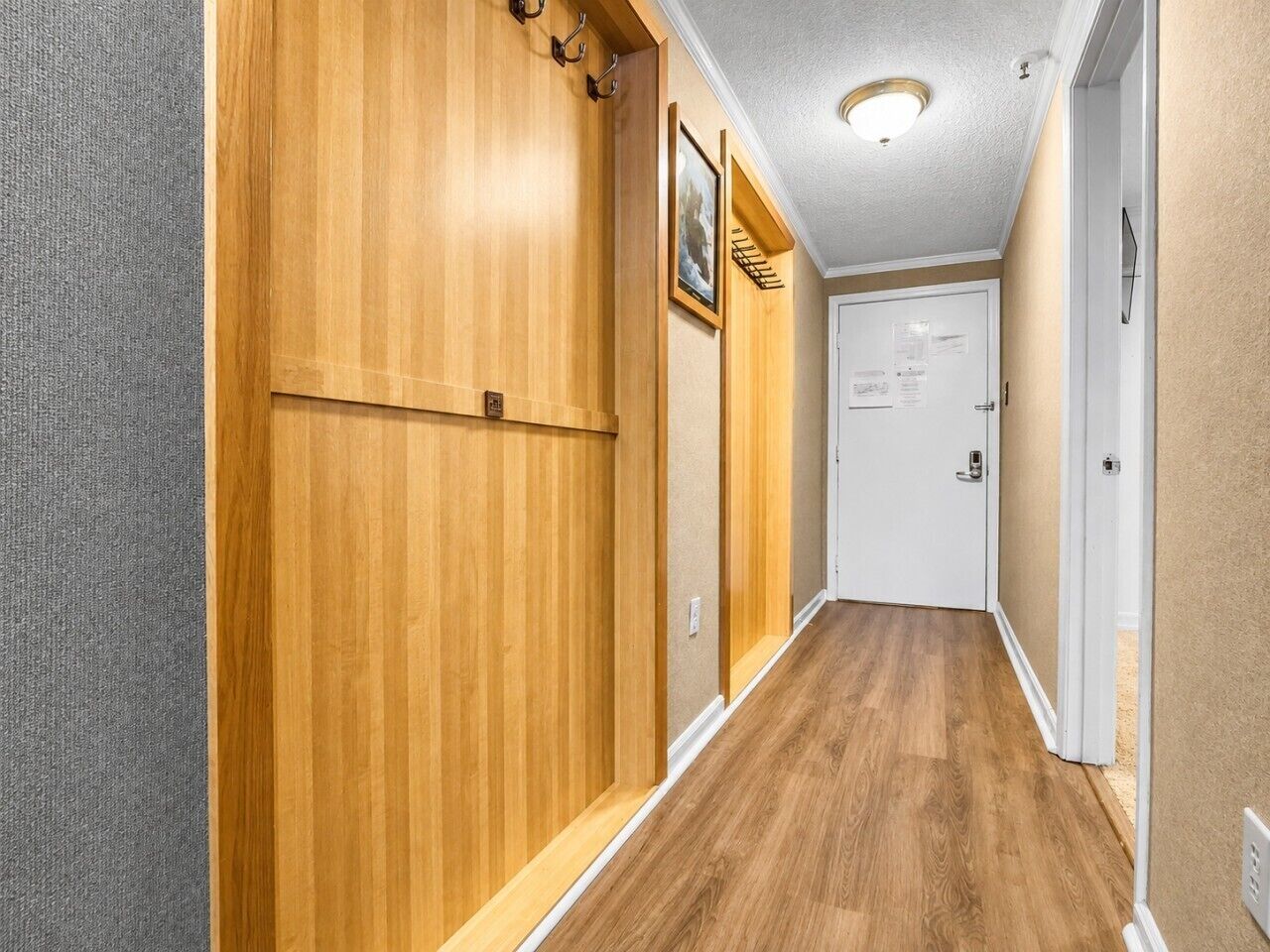 A hallway with wooden paneling, a white door, and a light fixture on the ceiling.