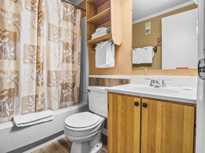 Un baño con inodoro, lavamanos y cortina de ducha.