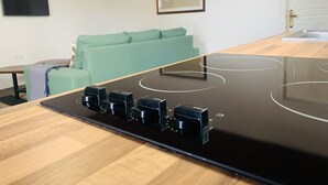 Een keuken met een zwart inductiefornuis en vier knoppen.
