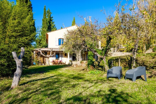 Ein Haus mit einer Terrasse, einem Essbereich und zwei Stühlen im Garten.