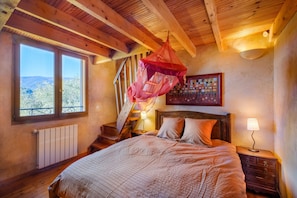 A bedroom with a bed, a nightstand, a lamp, a window with a view, and a staircase. - Holiday Home 'Villa Provence Vue Panoramique -' with Mountain View, Private Pool and Wi-Fi (Fayence)