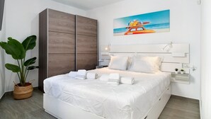 A bedroom with a bed, a large wardrobe, a potted plant, a painting, and a bedside table. - Holiday Home 'Casa Marion' with Private Terrace and Wi-Fi (El Golfo)